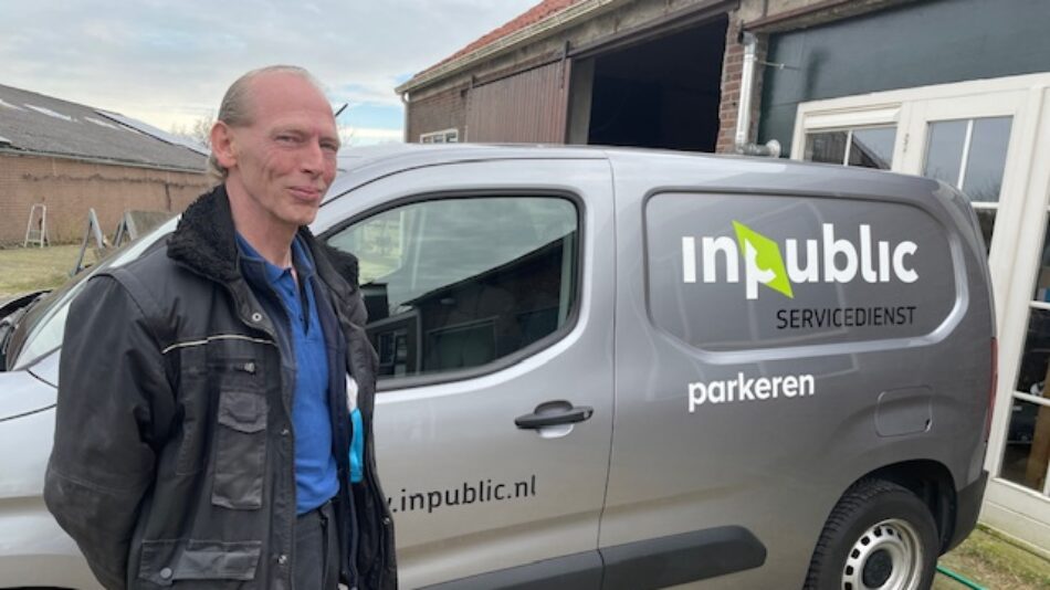 Servicebeheerder Peter van de Brand staat vriendelijk glimlachend bij de bedrijfswagen van InPublic.